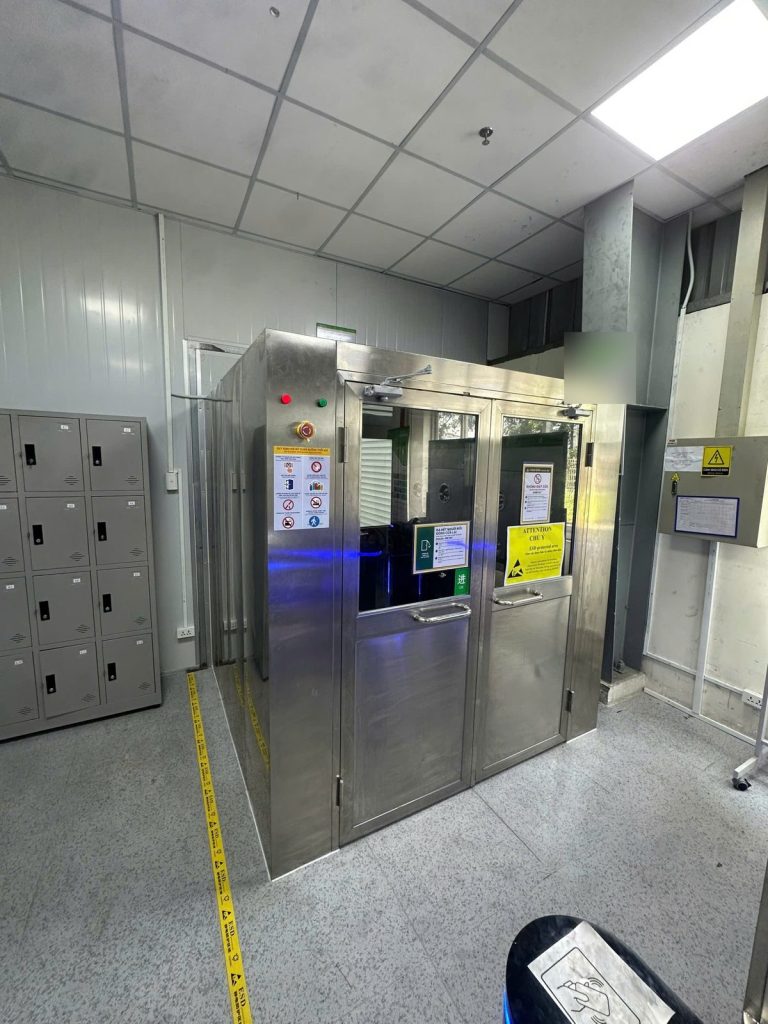 Lối vào khu sản xuất: buồng thổi khí, sàn kẻ băng keo ESD và biển